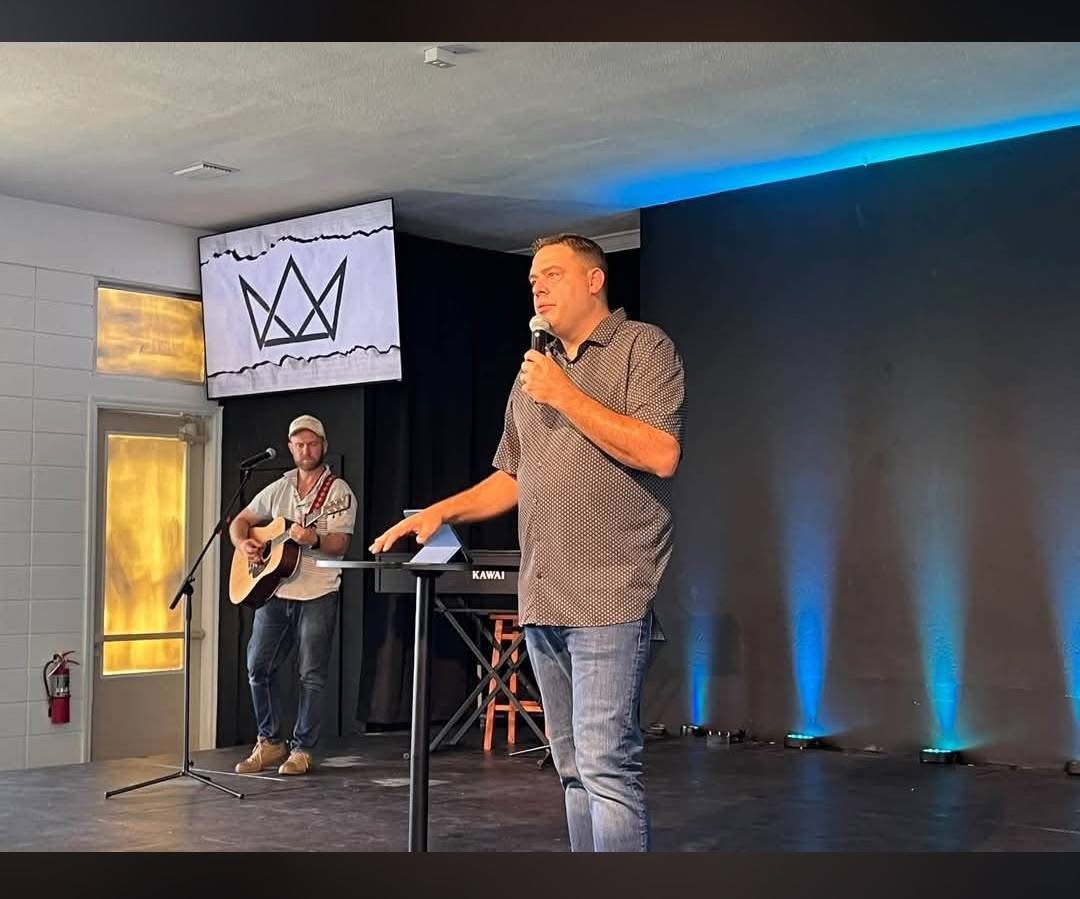 A speaker with a microphone and a guitarist during a service at Kingsway Church
